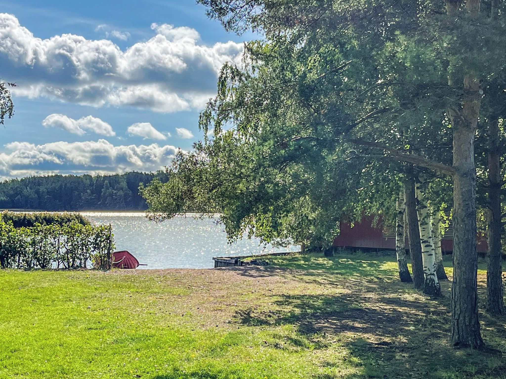 Une propriété située au bord d’un lac, avec une pelouse, un quai et un bâtiment rouge.