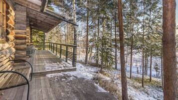 A wooden cabin with a covered porch and a bench.