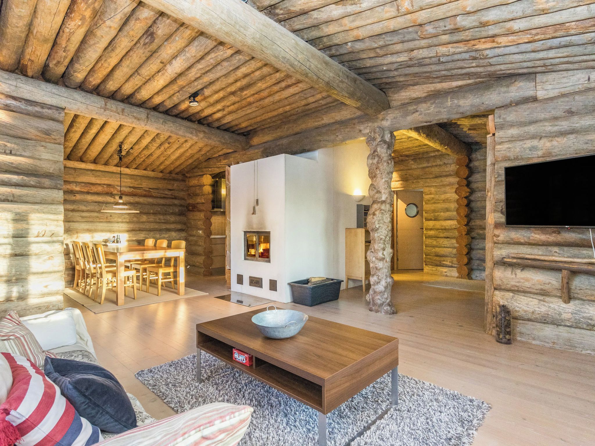 L’intérieur d’une cabane en rondins comprend un coin repas, une cheminée et un téléviseur.