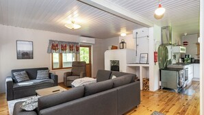 A modern living room with a sofa, a fireplace, and a kitchen area.
