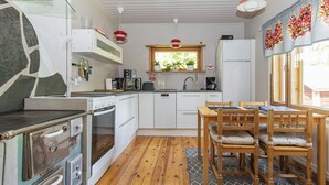 A compact kitchen with a stove, oven, sink, and a dining area with wooden chairs and a table.