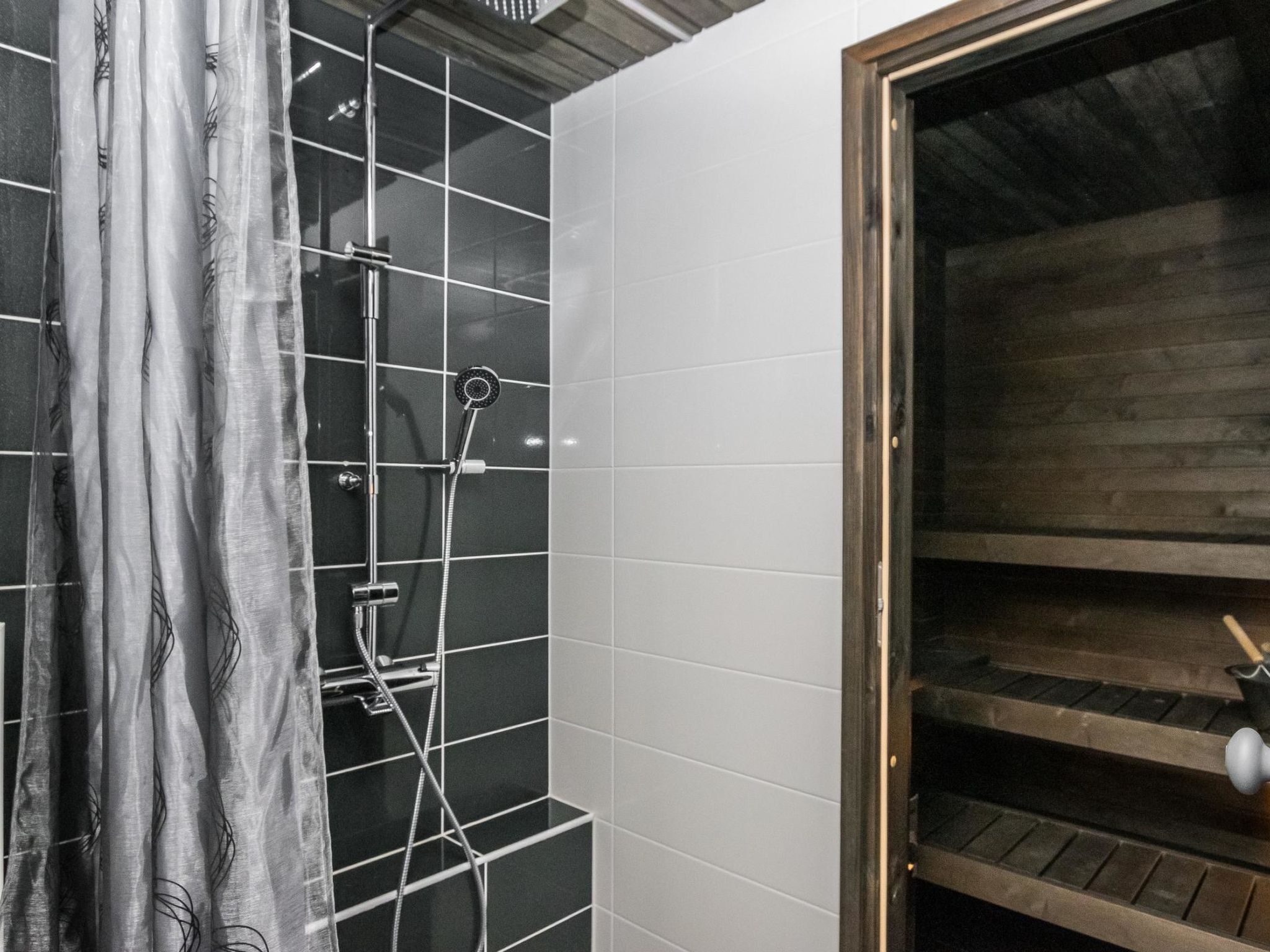 Une salle de bain avec une douche, des murs carrelés et une étagère en bois.