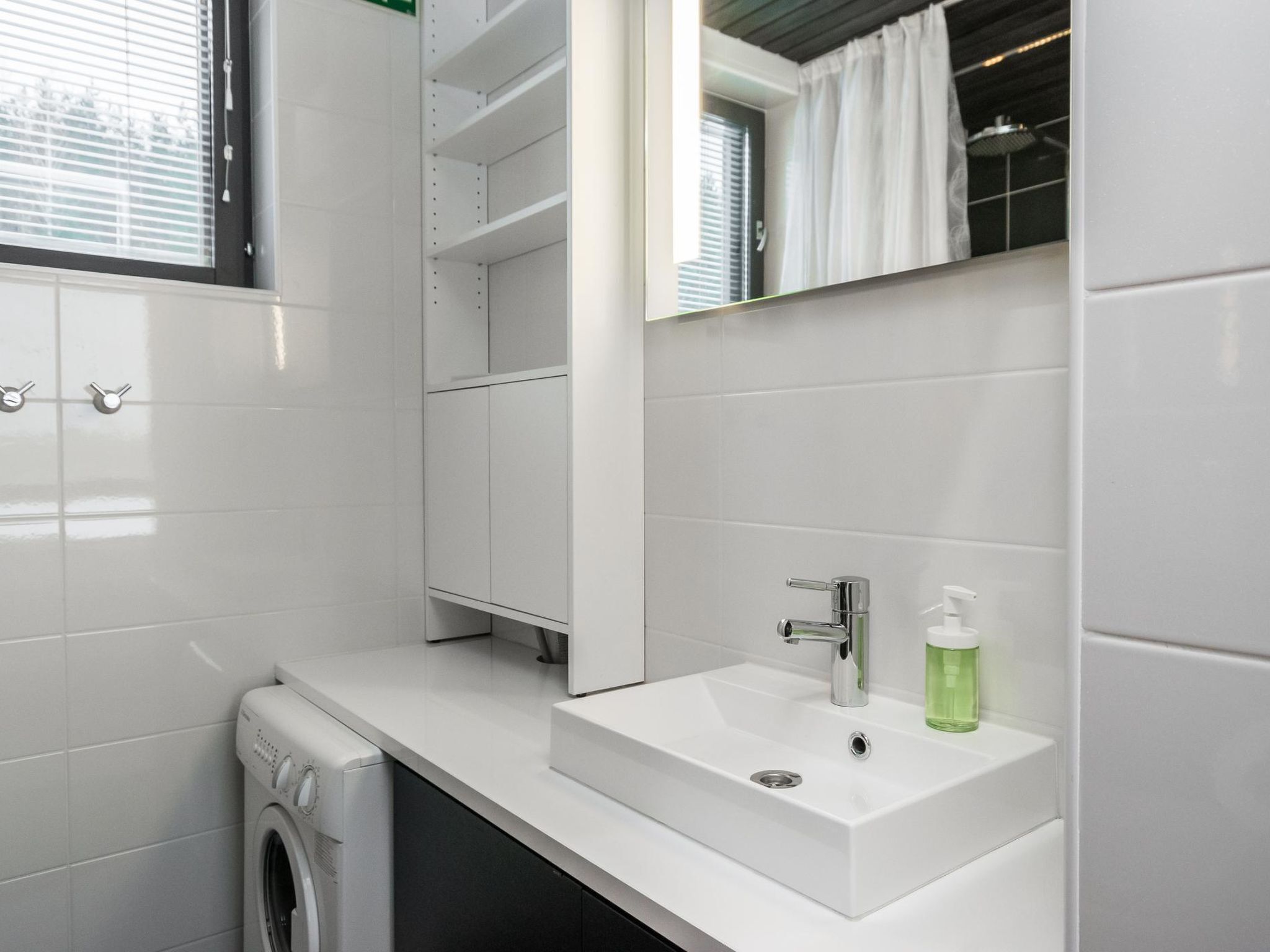 Une salle de bain moderne avec un lavabo blanc, un miroir et un lave-linge.