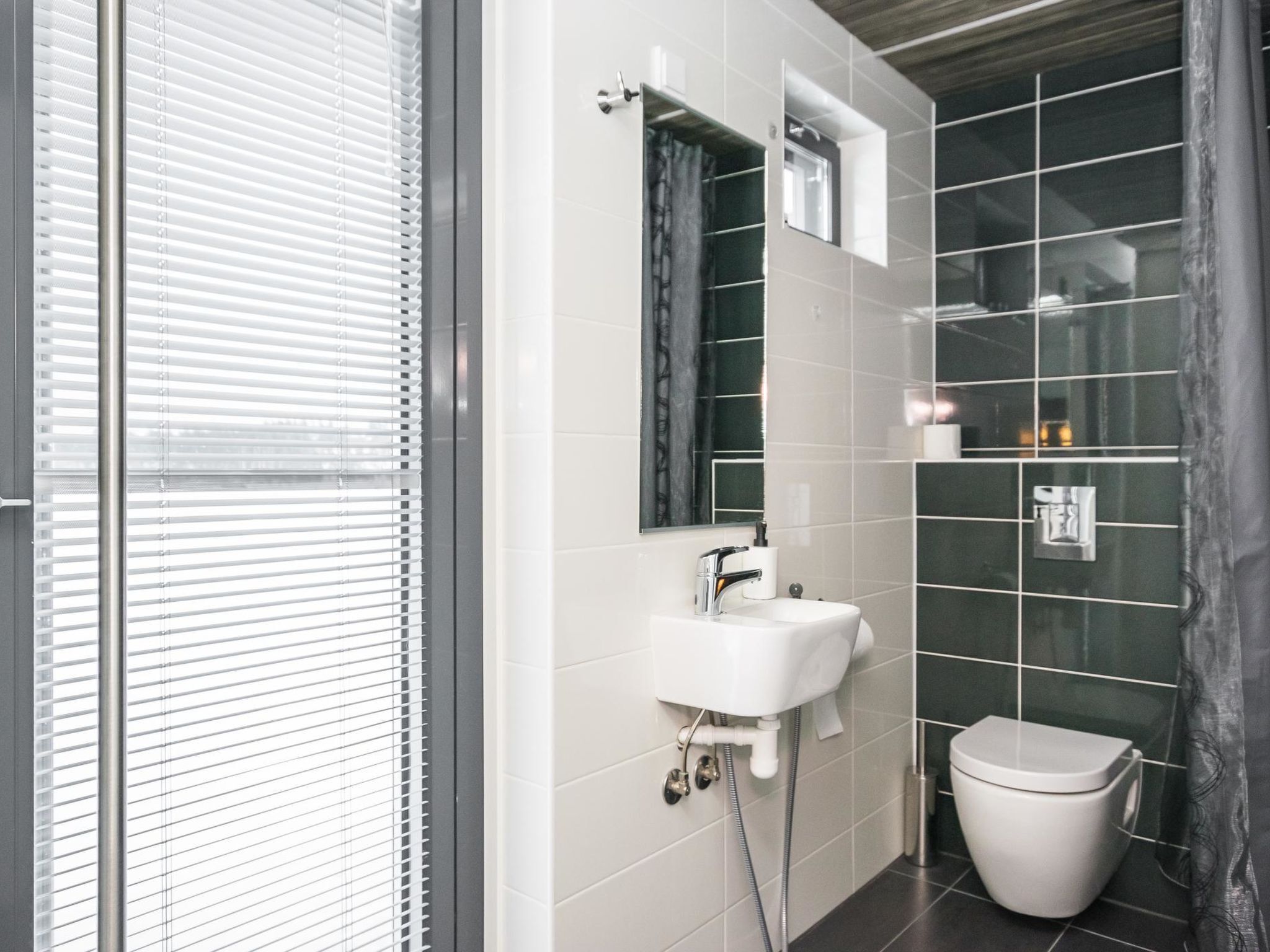 A modern bathroom with a white sink, mirror, and toilet.