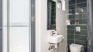 A modern bathroom with a white sink, mirror, and toilet.