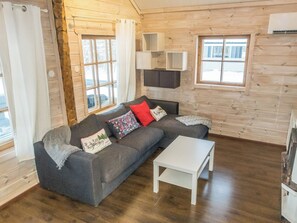 A cozy log cabin interior with a sofa, a small table, and a window with a view of the outside. - Puljunharju by Interhome (Sodankylä)