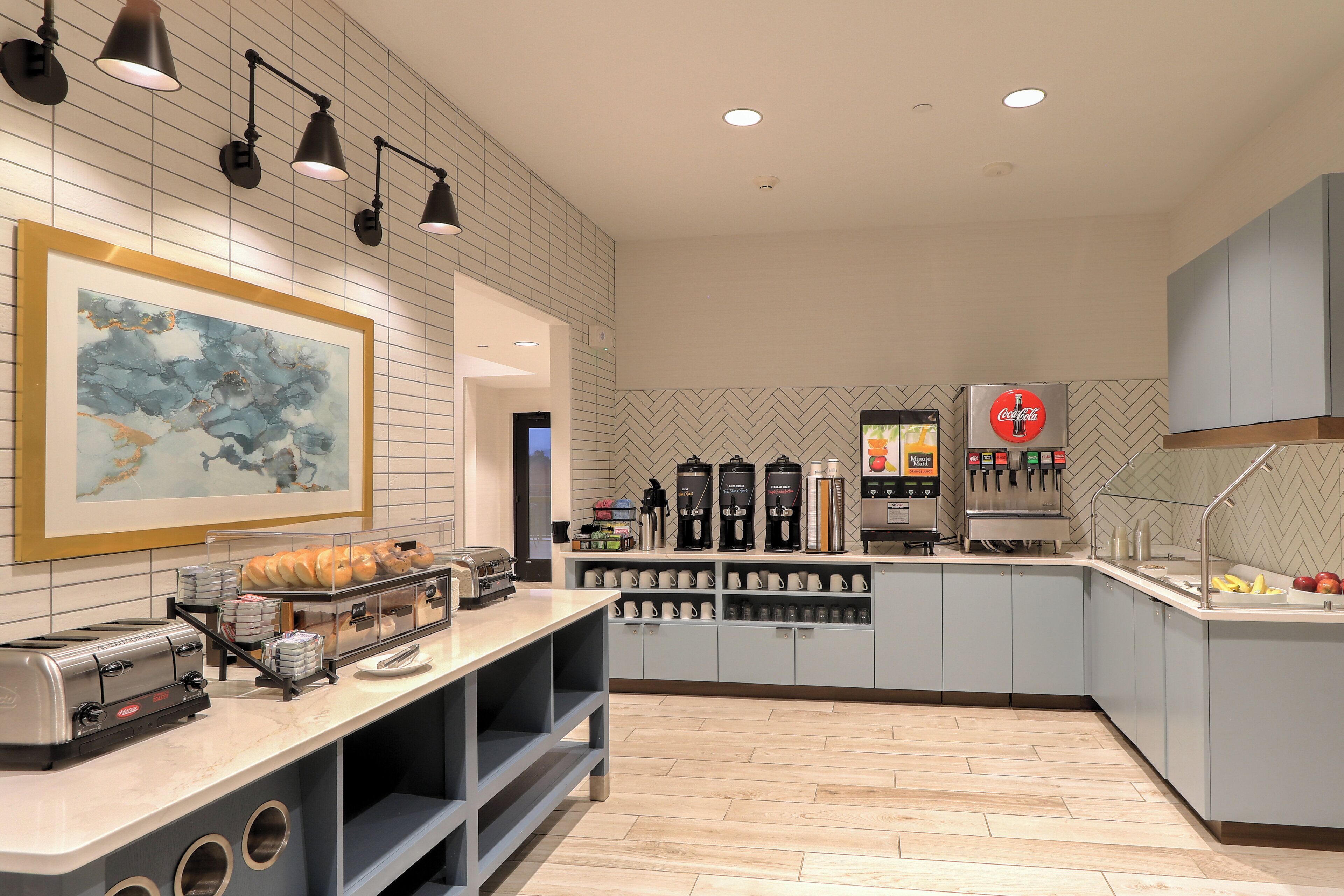 A modern kitchen with a coffee station, a framed artwork, and a vending machine.