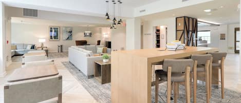Un vaste espace de vie comprenant un îlot central, un coin salon et une cuisine.