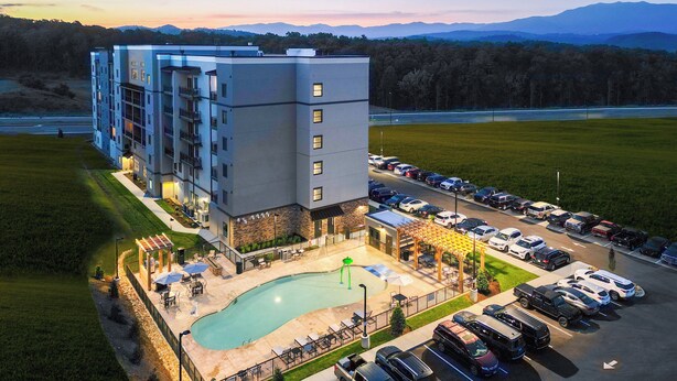 Un hotel de varios pisos con piscina, zona de estar al aire libre y estacionamiento.