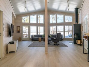 Un salon spacieux doté d’une grande fenêtre, d’une cheminée et d’un téléviseur fixé au mur.