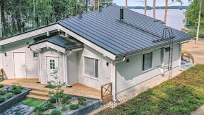 Una casa moderna con techo inclinado, un porche delantero y vistas a un lago.