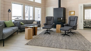 Un salón amplio con techo alto, ventanas grandes, chimenea empotrada y muebles modernos.