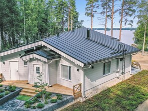 Une maison moderne avec un toit en métal, une terrasse en bois et un petit jardin.
