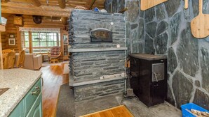 A stone fireplace with a pizza oven, wooden beams, and a stone wall.