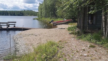 A lakeside cabin with a dock extending into the water, surrounded by trees and a picnic table.