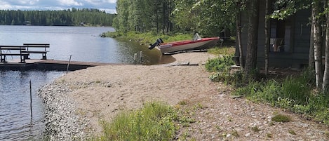 Un chalet au bord du lac, doté d’une jetée qui s’avance dans l’eau, entouré d’arbres et agrémenté d’une table de pique-nique.
