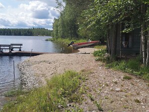 Un chalet au bord du lac, doté d’une jetée qui s’avance dans l’eau, entouré d’arbres et agrémenté d’une table de pique-nique.
