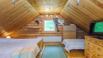 Quarto de sótão acolhedor com duas camas, uma cômoda, uma televisão e uma janela com vista para o exterior.