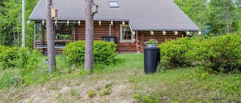 Eine Blockhütte mit geneigtem Dach, einer Veranda und einem Schornstein.