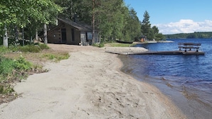 A sandy beach with a wooden dock and a small cabin.
