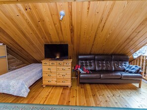 A wooden interior with a television on a wooden dresser, a brown leather sofa, and a small bed. - Kokkoranta by Interhome (Ilomantsi)