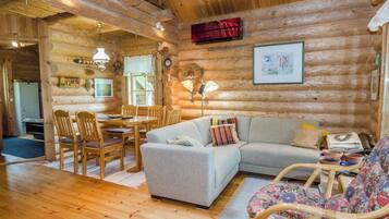 Ein gemütliches Blockhaus-Interieur mit Essbereich, einer Couch und einem Schaukelstuhl.