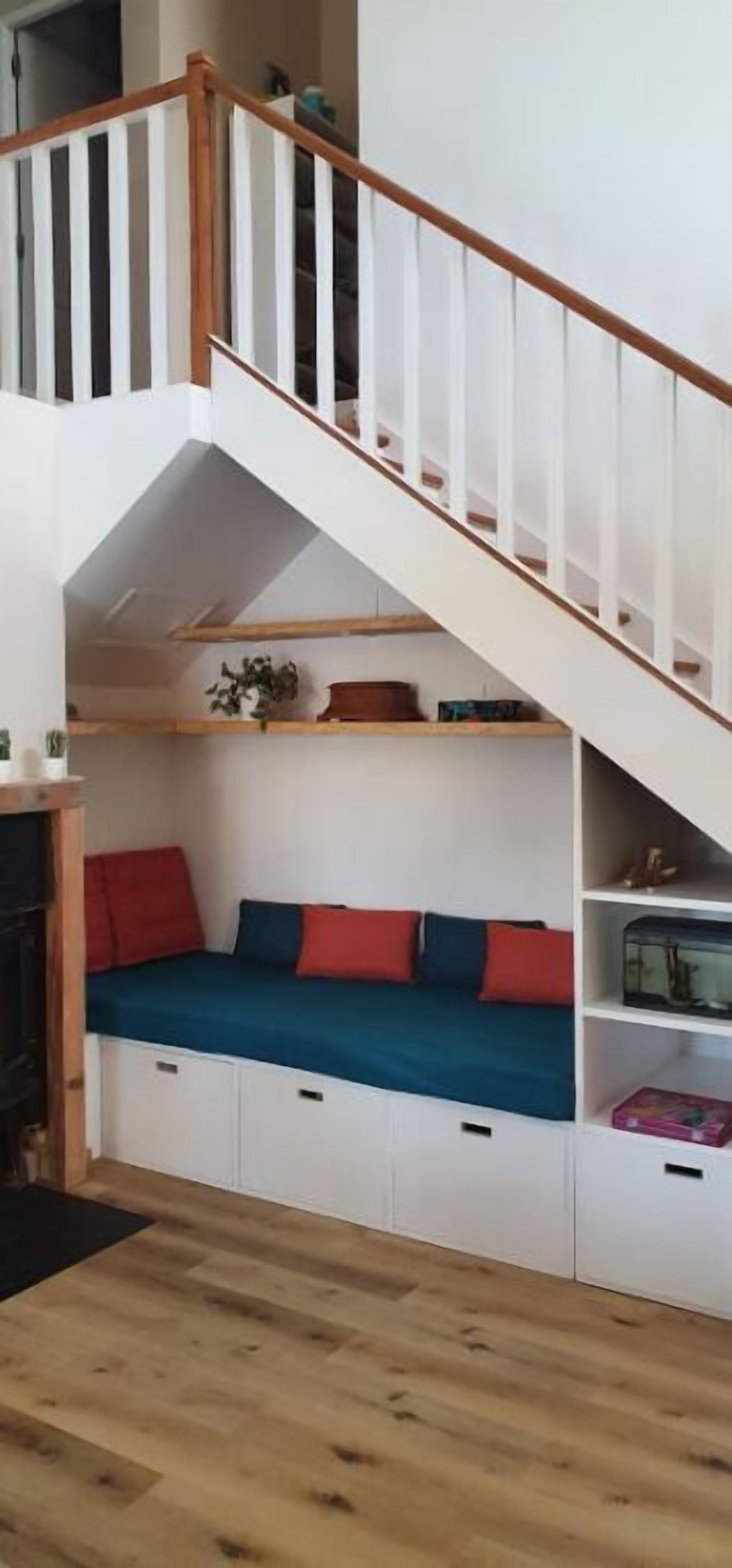 Une pièce de style « loft », dotée d’un escalier en bois, de sièges intégrés avec des coussins et d’armoires de rangement.