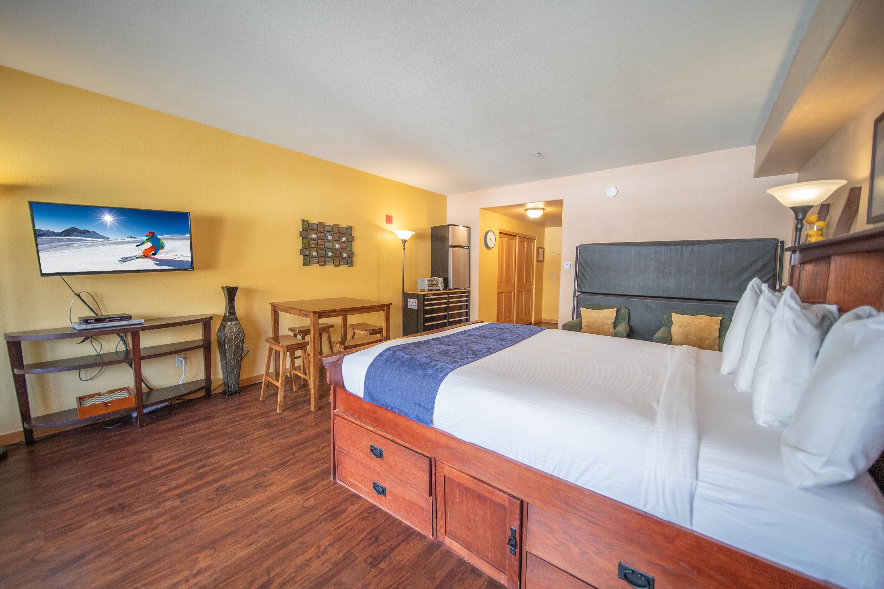 A hotel room with a large bed, wooden furniture, a flat-screen TV, and a small desk.