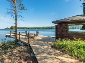 Eine Holzsteg, der zu einer Hütte mit Seeblick und Blick auf den Wald führt.