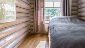 Une chambre de style rustique, avec un lit, des murs en bois et une fenêtre avec des rideaux.