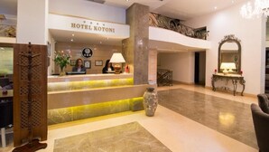 Un vestíbulo de hotel con una recepción, un jarrón grande y una araña.