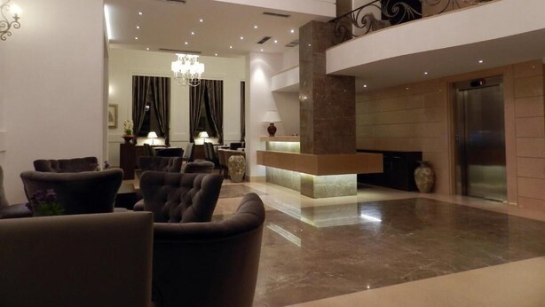 Un vestíbulo amplio con candelabro, un mostrador de recepción y una escalera moderna.
