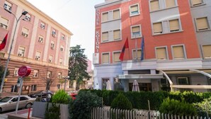 Un hotel con fachada roja y blanca, varias ventanas y una bandera.