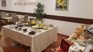 Una mesa de buffet en el Hotel Kotonai con distintos tipos de comida y un cartel en la pared.