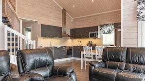 A modern living room with leather sofas and a kitchen area with dark cabinets and a microwave. - Mökki tenolla by Interhome (Utsjoki)