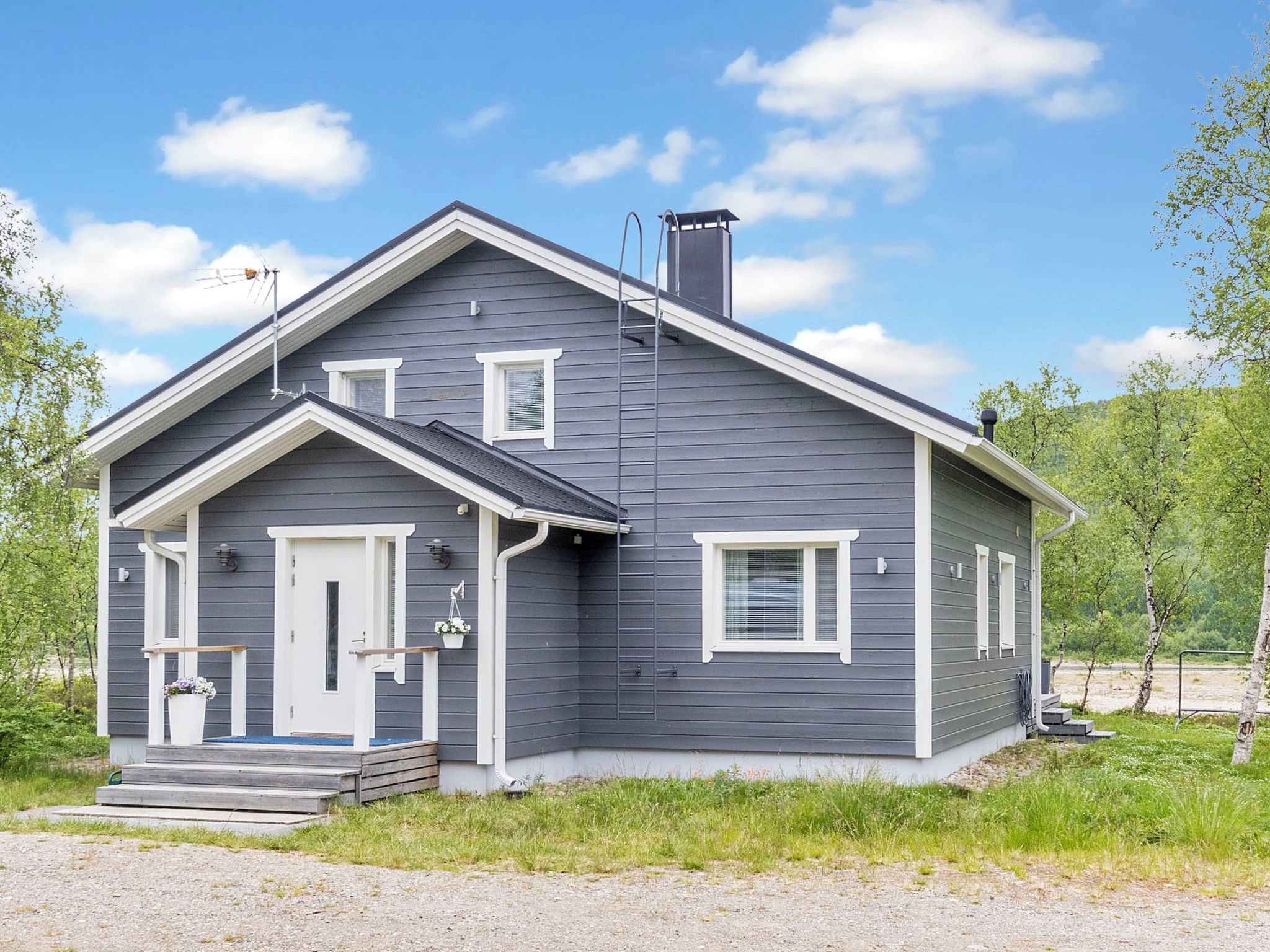 A two-story house with a front porch, a chimney, and a satellite dish.
