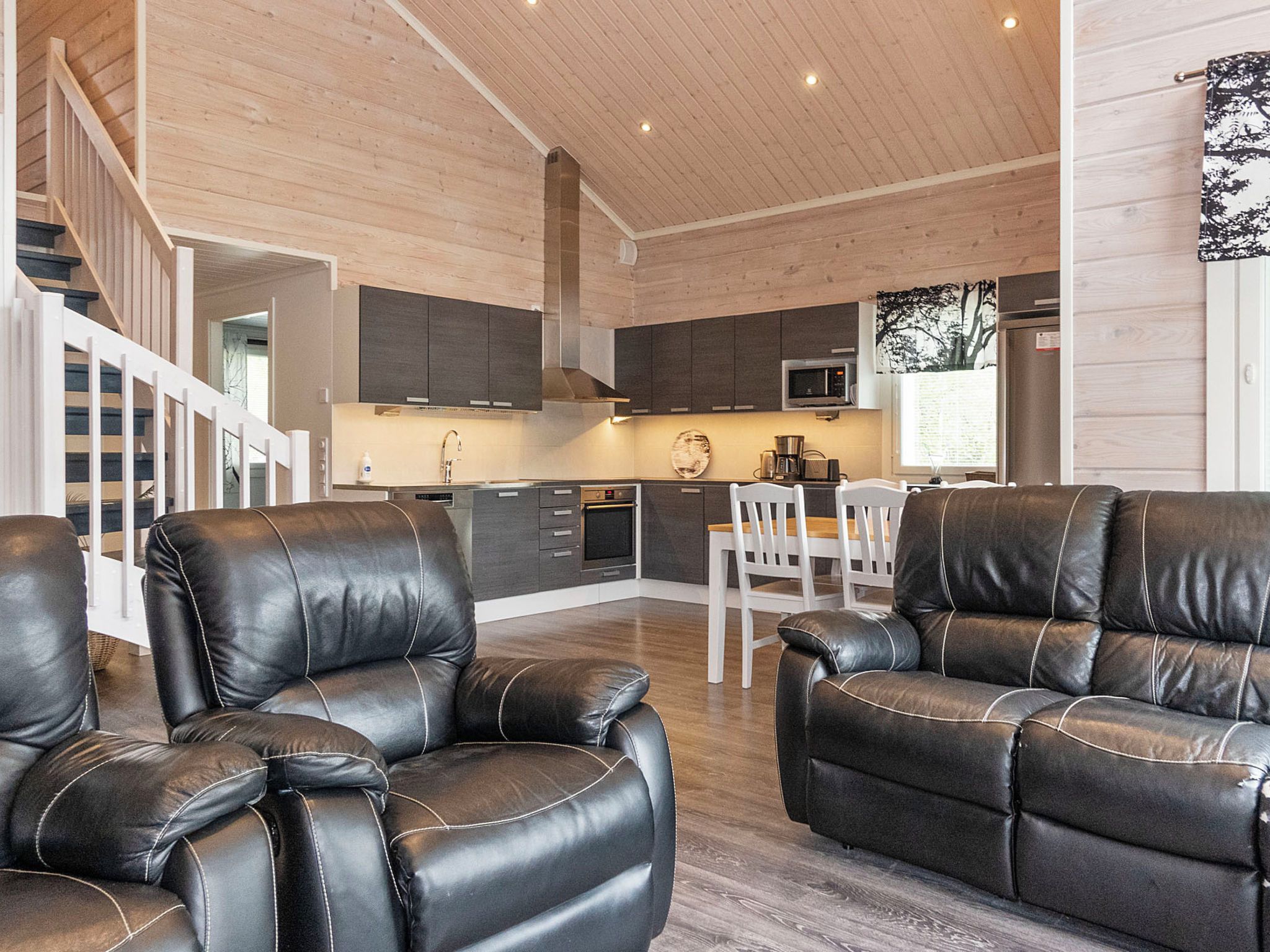 Un intérieur moderne avec des canapés en cuir, une cuisine et un escalier.