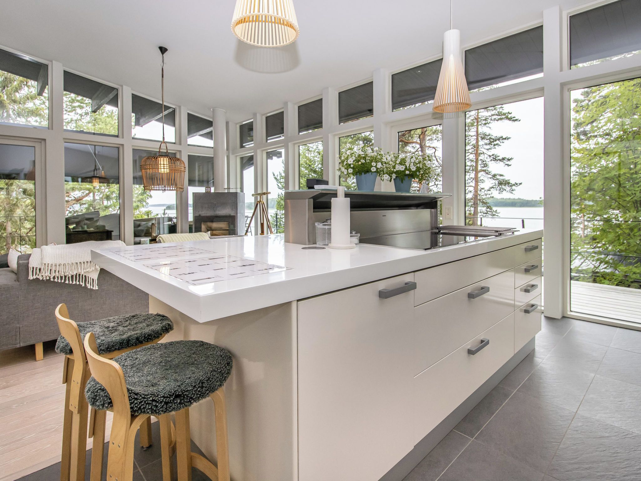 A modern kitchen with a large island, bar stools, and a view of the outdoors.