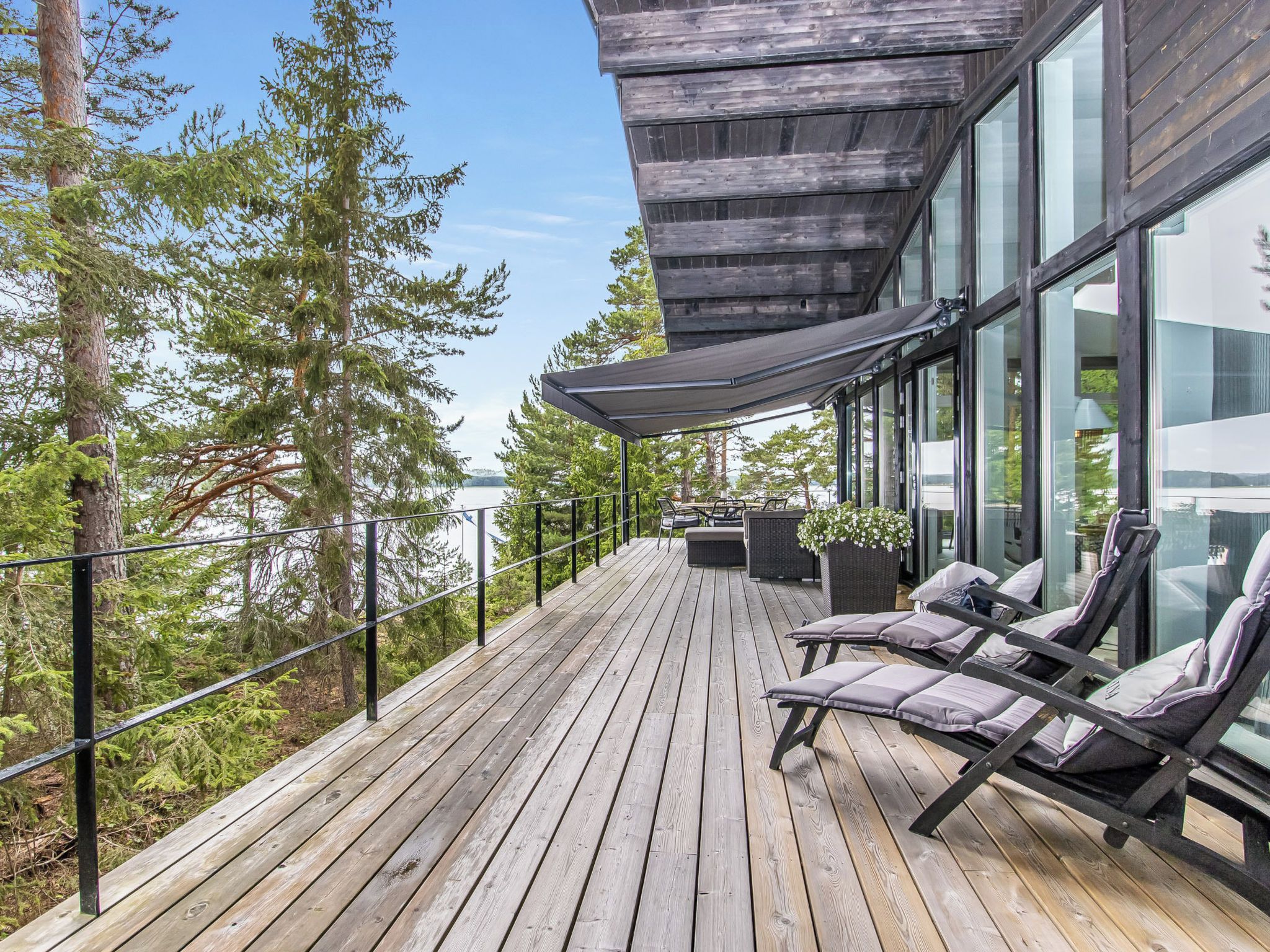 A wooden deck with outdoor seating and a glass-enclosed room.
