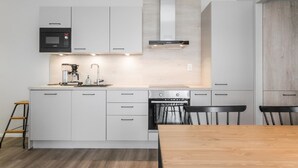 Una cocina moderna con armarios blancos, una estufa de acero inoxidable y una mesa de comedor de madera.