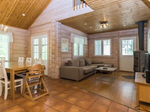 Ein Holzblockhaus-Interieur mit Essbereich, Sofa und Kamin.