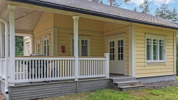 A yellow single-story house with a porch, a chimney, and a red fire hydrant.