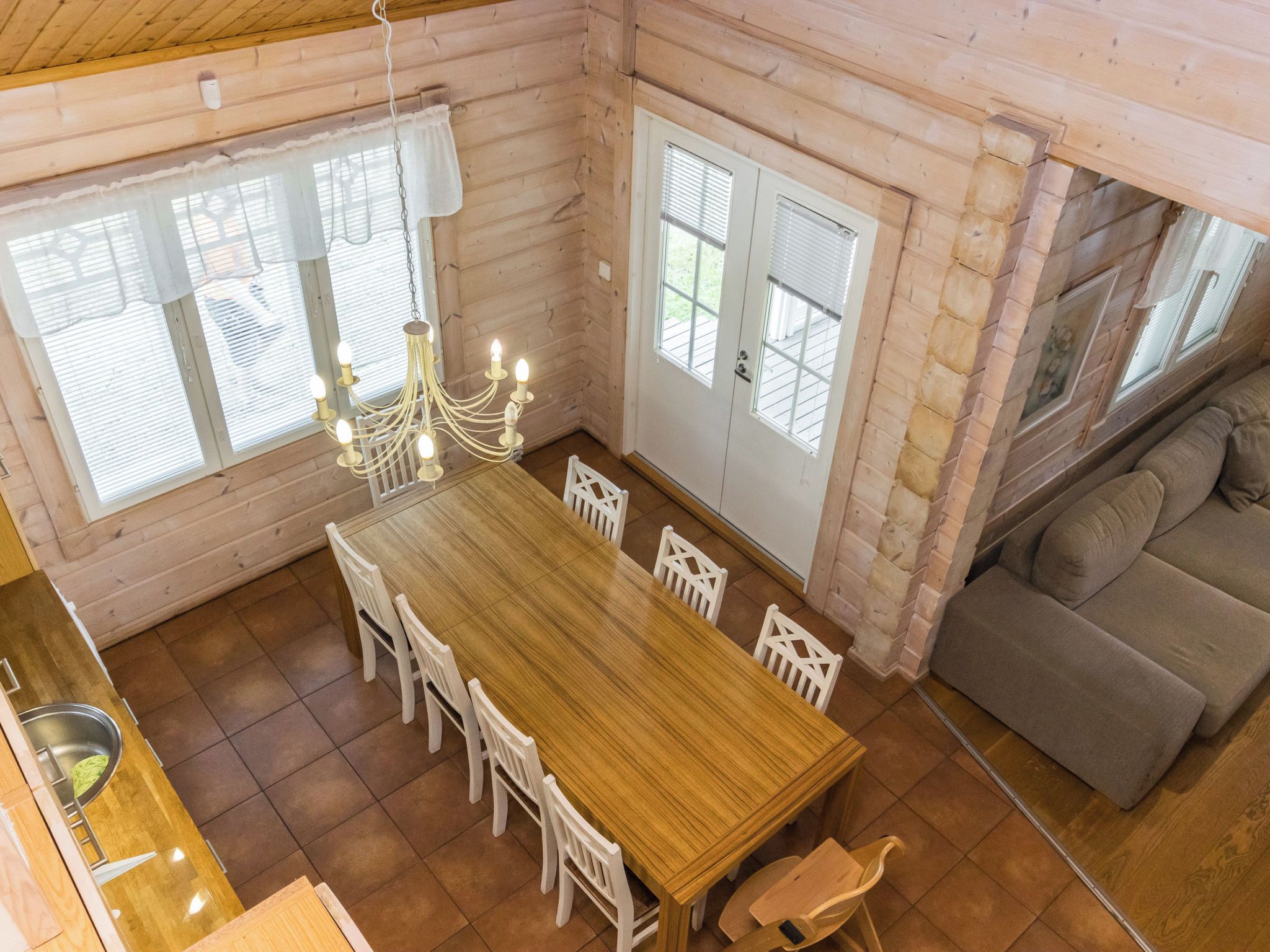 Un intérieur en bois comprenant une table à manger, des chaises, un lustre et un canapé.