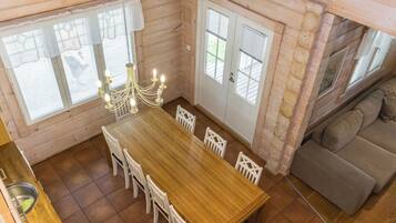 Un intérieur en bois comprenant une table à manger, des chaises, un lustre et un canapé.