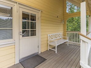 A wooden porch with a white bench, a door with a window, and a small outdoor light fixture. - Kuusikko by Interhome (Pori)