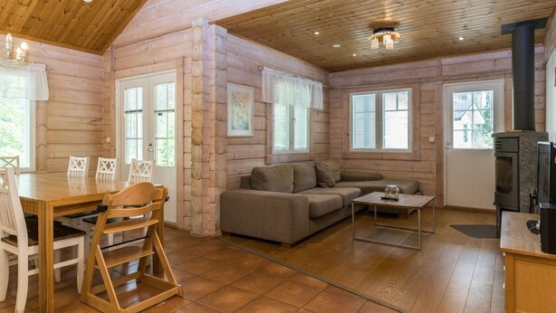 Acogedor interior de cabaña de madera con comedor, sofá y chimenea.