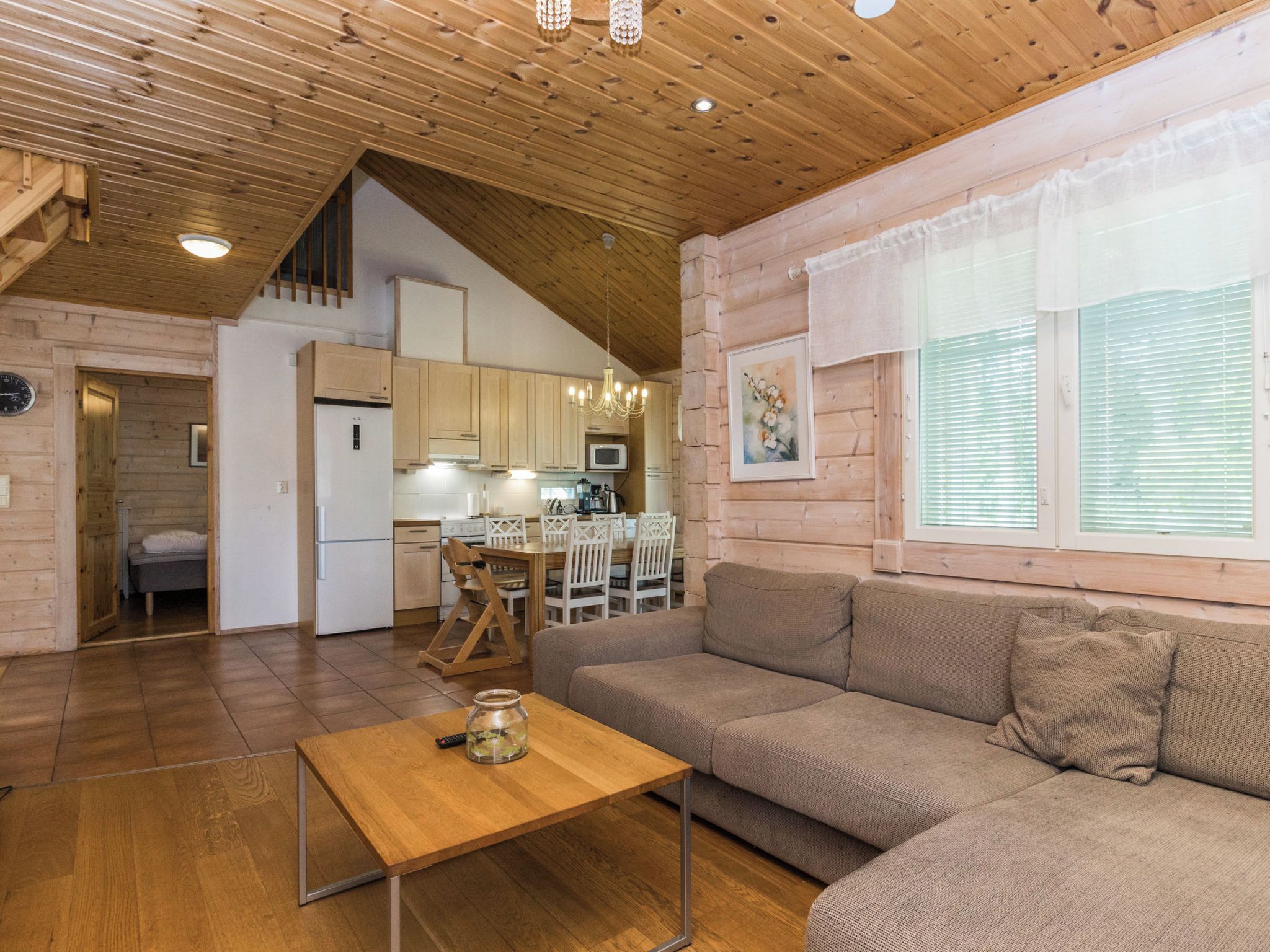 Un intérieur chaleureux avec un plafond en bois, un coin repas, un canapé et une cuisine.