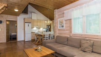 Un intérieur chaleureux avec un plafond en bois, un coin repas, un canapé et une cuisine.