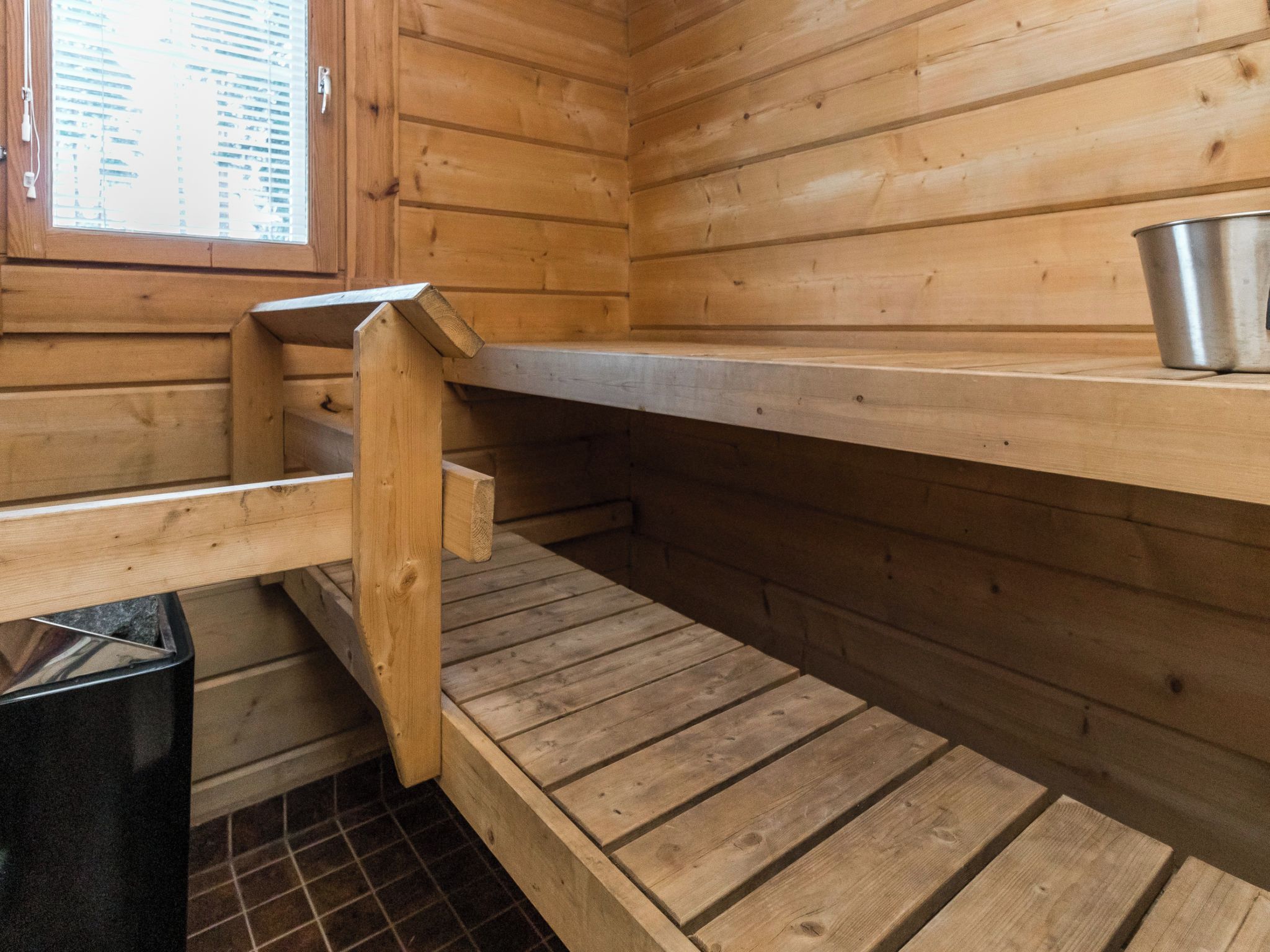 A wooden interior with a window, a metal bucket, and a tiled floor.