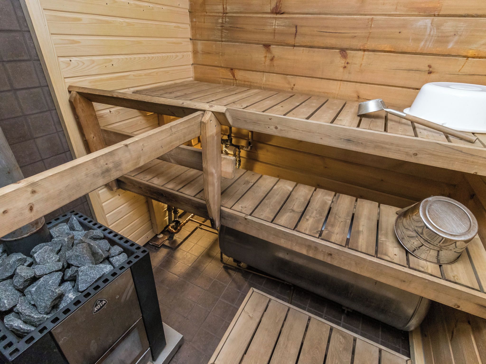 A sauna with wooden benches and a stone heating element.